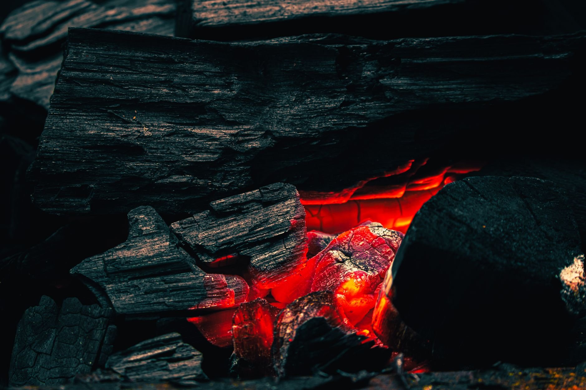 Close-up of glowing charcoal embers with dramatic warm lighting