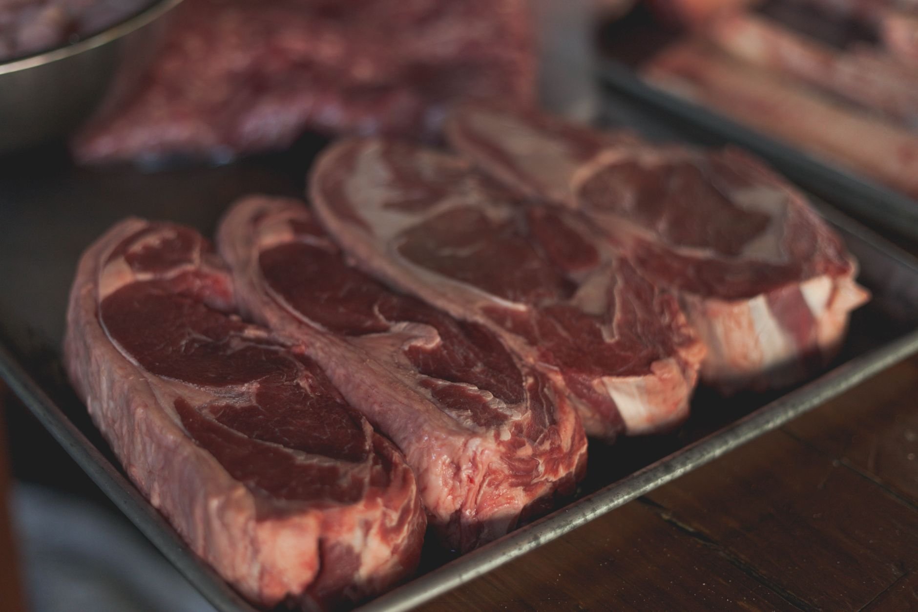 High-quality raw steaks on a metal tray, ready for cooking